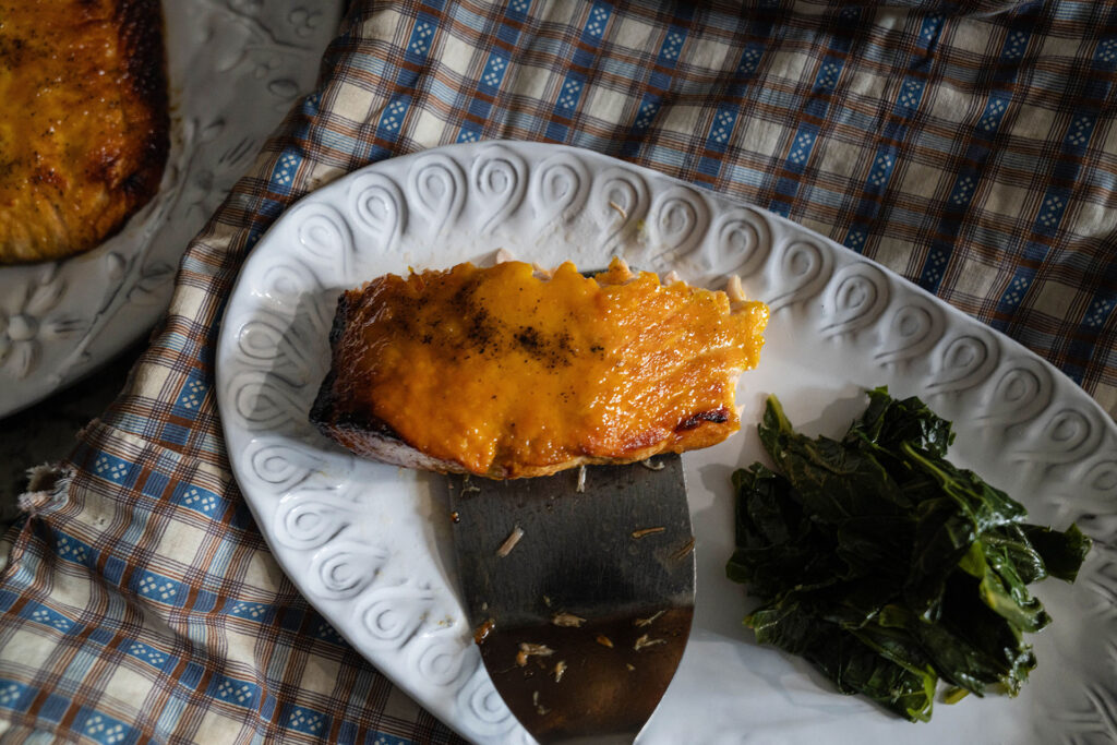 air fried salmon on a white place with a side of collard greens