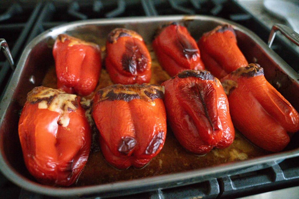 fresh roasted and stuffed red bell peppers in a roasting pan