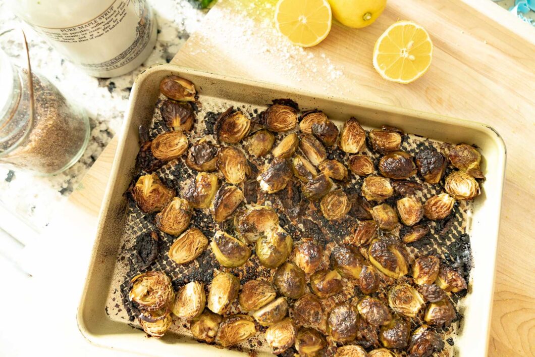 air fried brussel sprouts on a serving pan with sliced lemon