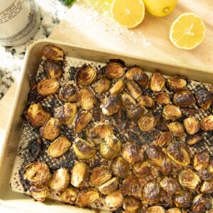 air fried brussel sprouts on a serving pan with sliced lemon