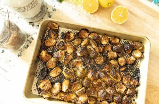 air fried brussel sprouts on a serving pan with sliced lemon