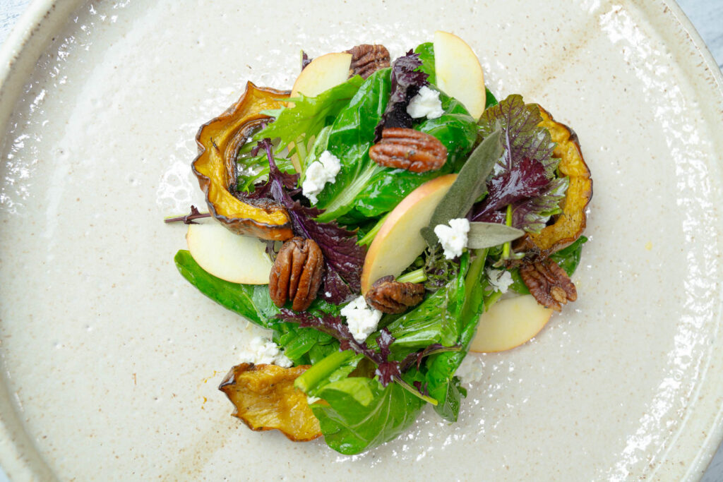 Delicata Squash Salad with Roasted Pecans and Apple Cider Vinaigrette salad presented on a serving plate